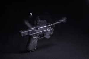 fired black semi automatic pistol emitting smoke